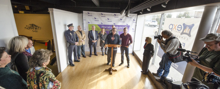 Developer Dick Anagnost, with his son Alexander, speaks during a news conference at the site of a future community recovery center that he is investing in, along with Andy Crews of AutoFair.