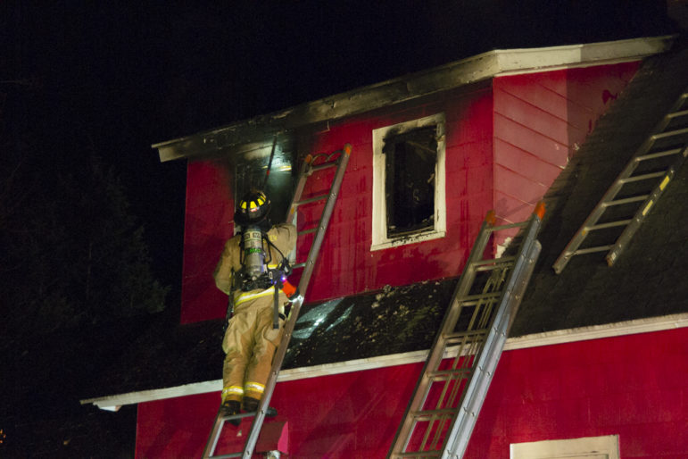 A firefighter climbs a ladder to check out the second-floor at 54 Carroll St., scene of a fire on Dec. 20..