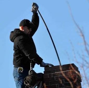 John Ceaser of Ceaser Chimney Service LLC sweeping a chimney.