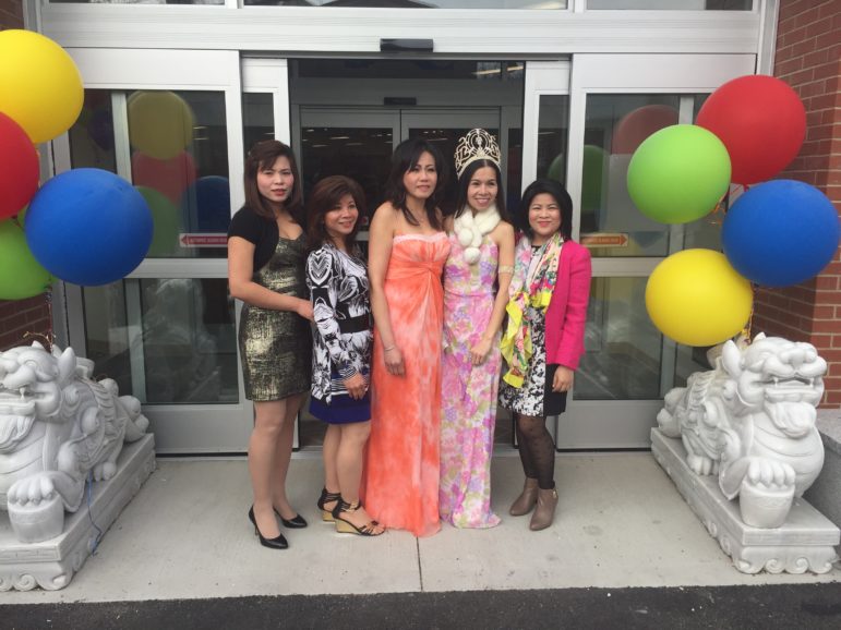 Friends and relatives take turns posing for photos in front of the new Saigon Asian Market, celebrating the ribbon cutting on Feb. 29.