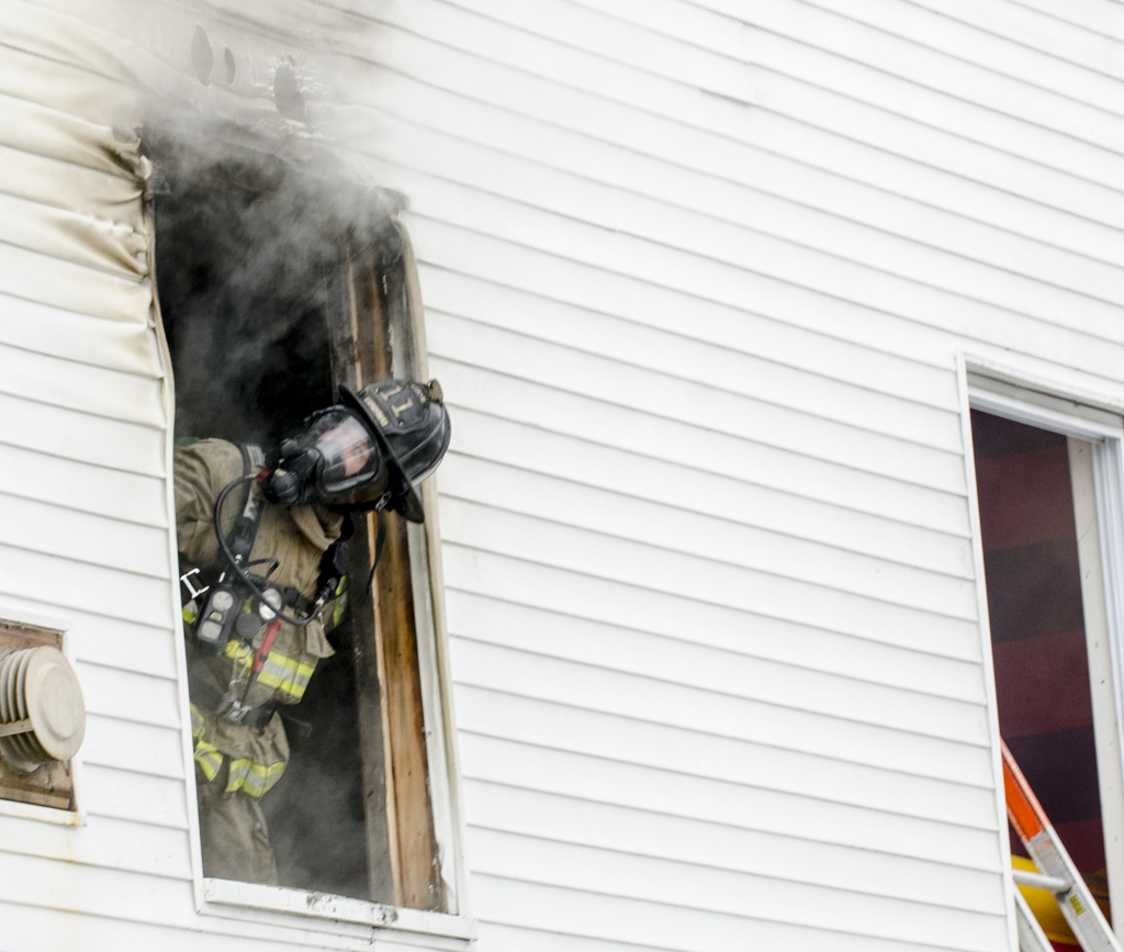 A firefighter sticks his head out a window that had been knocked out to vent the blaze at 297 Concord St.