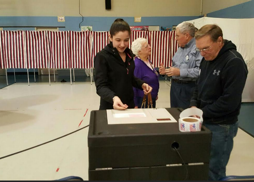 Katelynn Theodore, 18, first-time voter, slides her ballot into the machine at Ward 9 Bishop O'Neil Youth Center on South Elm Street.
