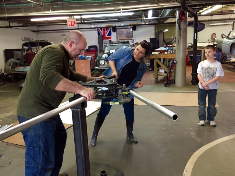 James Beer, left, and Christina Pitsch, center use a tube bender to fashion a bike rack as Jack Beer waits in the wings, to run the part to his Aunt, Vivian Beer, who was constructing the bike racks as part of a team effort for the #E4K challenge.