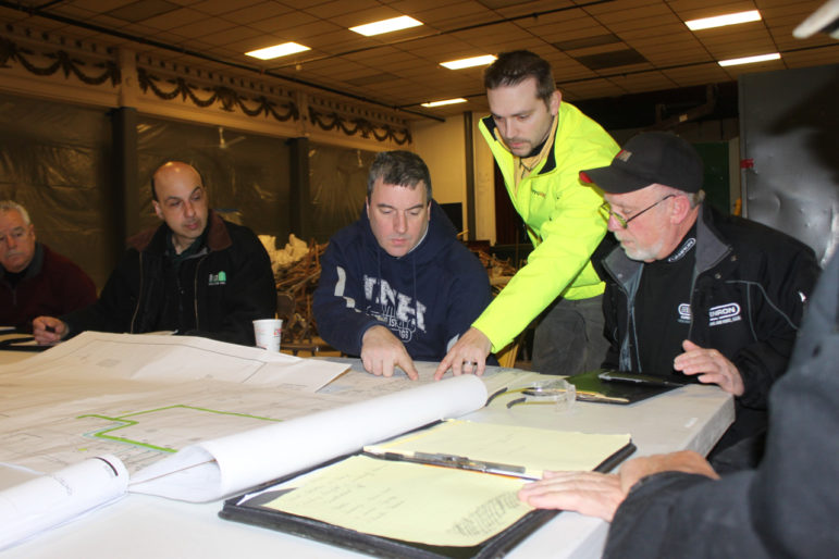 Construction team huddle over the blueprints for the MPAL building renovation.