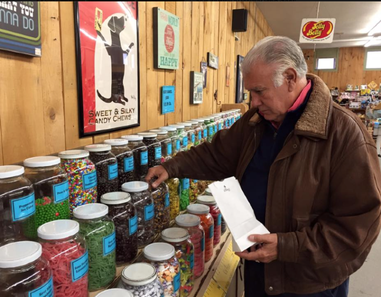 Manchester Mayor Ted Gatsas indulges in the candy bar at Chutters during a campaign stop in Littleton.