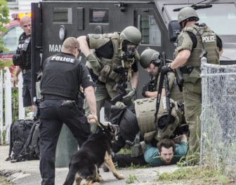 SWAT agent and a police dog surround a man who was barricaded Wednesday morning on Krakow Avenue.