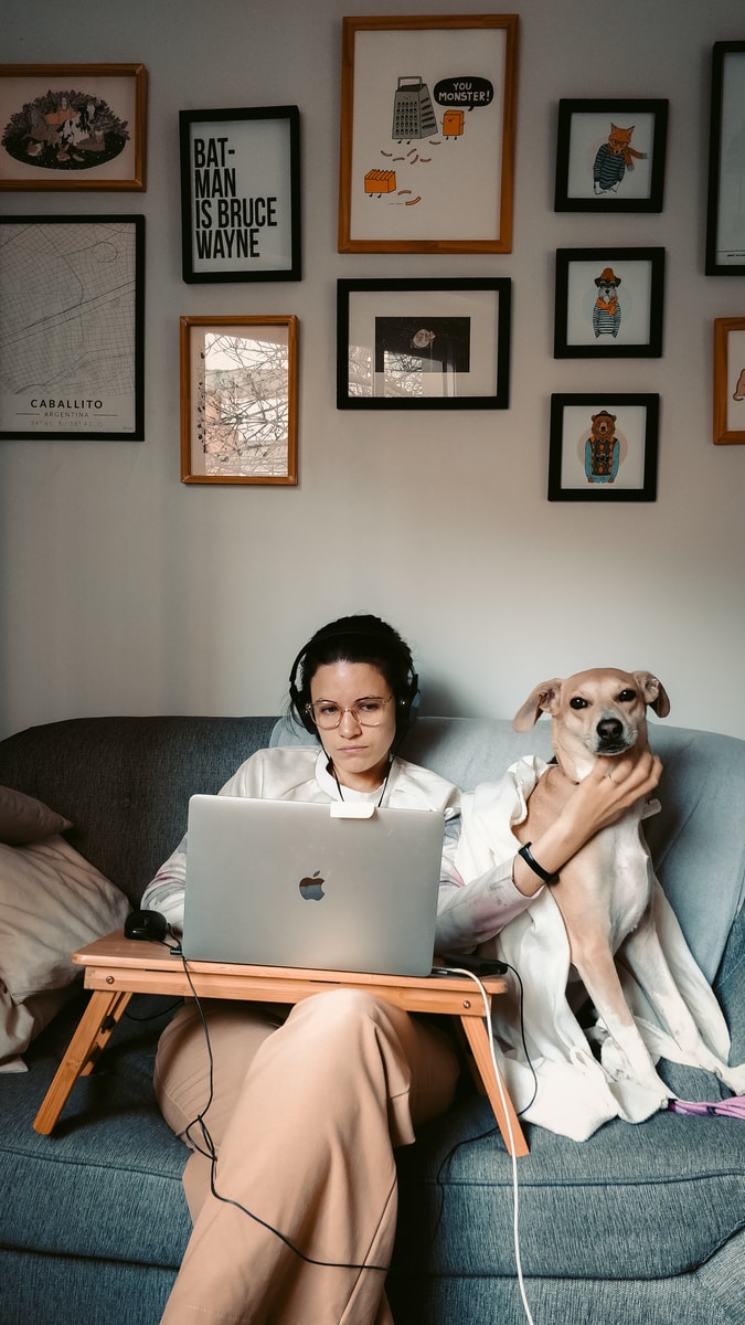 woman in white long sleeve shirt sitting on gray couch with macbook