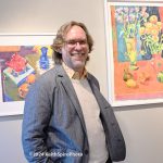 Artist Bruce McColl standing between two of his watercolors on display at Sullivan Fine Art Gallery. A photograph by Keith Spiro